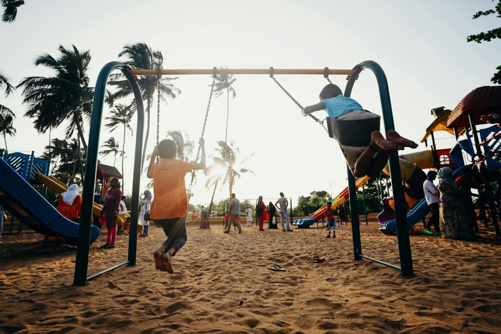pexels-photo-4430308-4430308 Kids swinging and enjoying a fun day at a tropical playground.